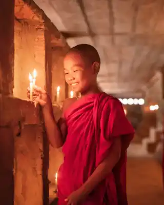 Buddhist monks rlighting candles in Bagan, Myanmar.